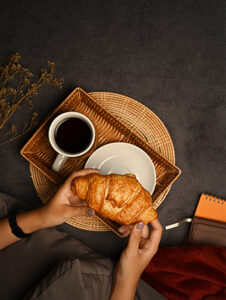 Above view of woman holding fresh baked croissant.