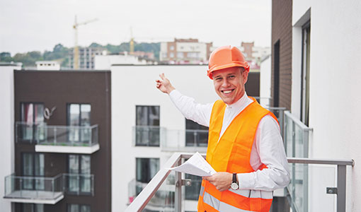 Young architect wearing a protective helmet standing on the mountains building outdoor background