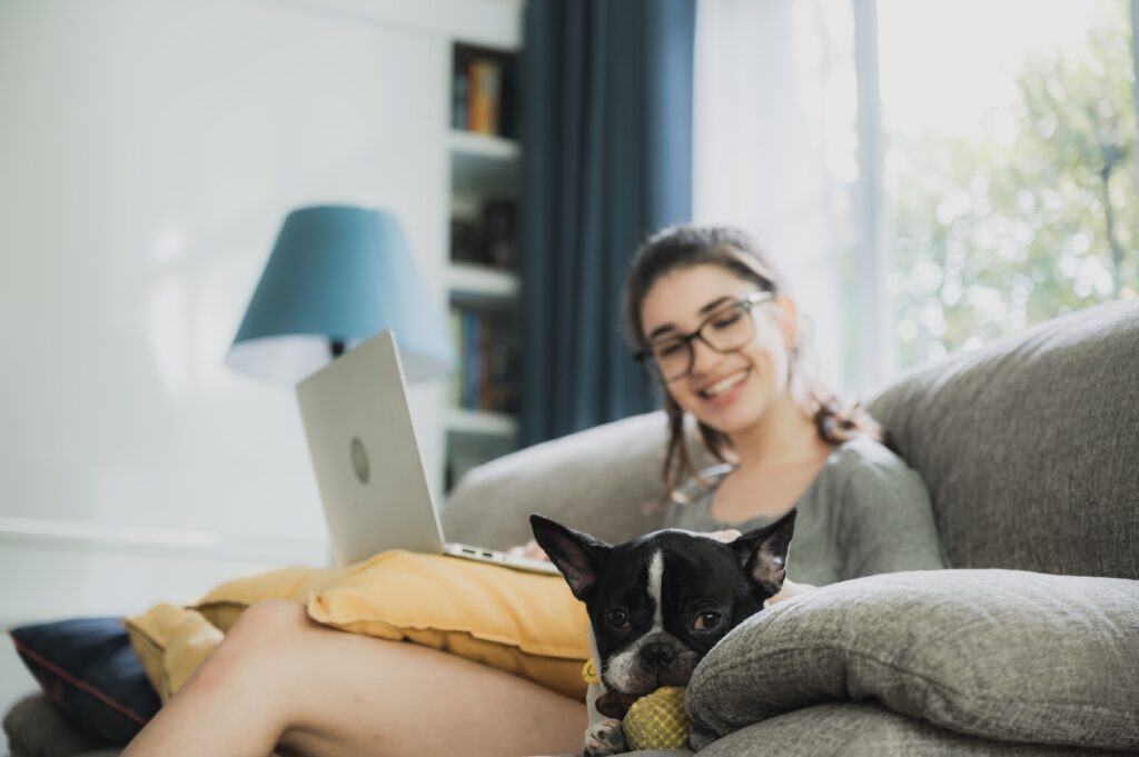 Funny and cheerful girl watching comedy movie on laptop with spectacles and pet dog
