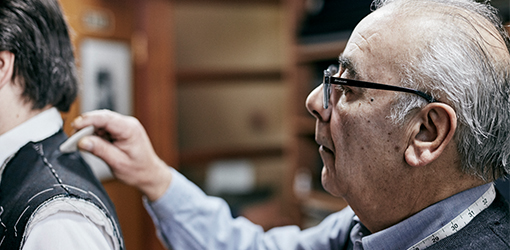 Tailor fitting a jacket on a customer using tailor's chalk to mark the fabric.