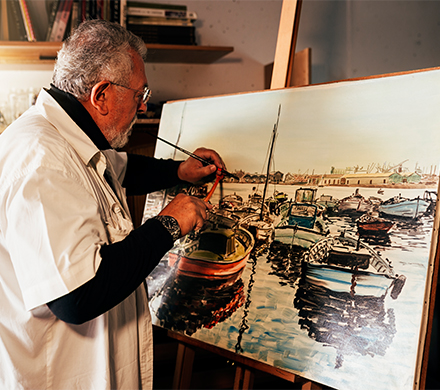 Old man artist painting oils in his studio.